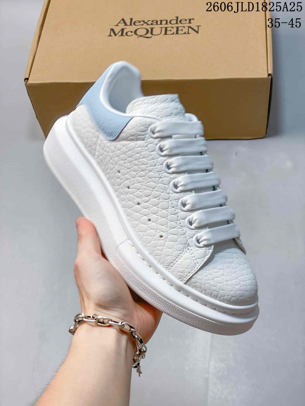 Side view of a white textured sneaker with pale blue heel panel and thick white sole; size range 35–45 appears in the image.