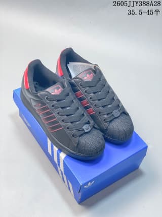Pair of dark sneakers with red accents displayed on a blue shoe box