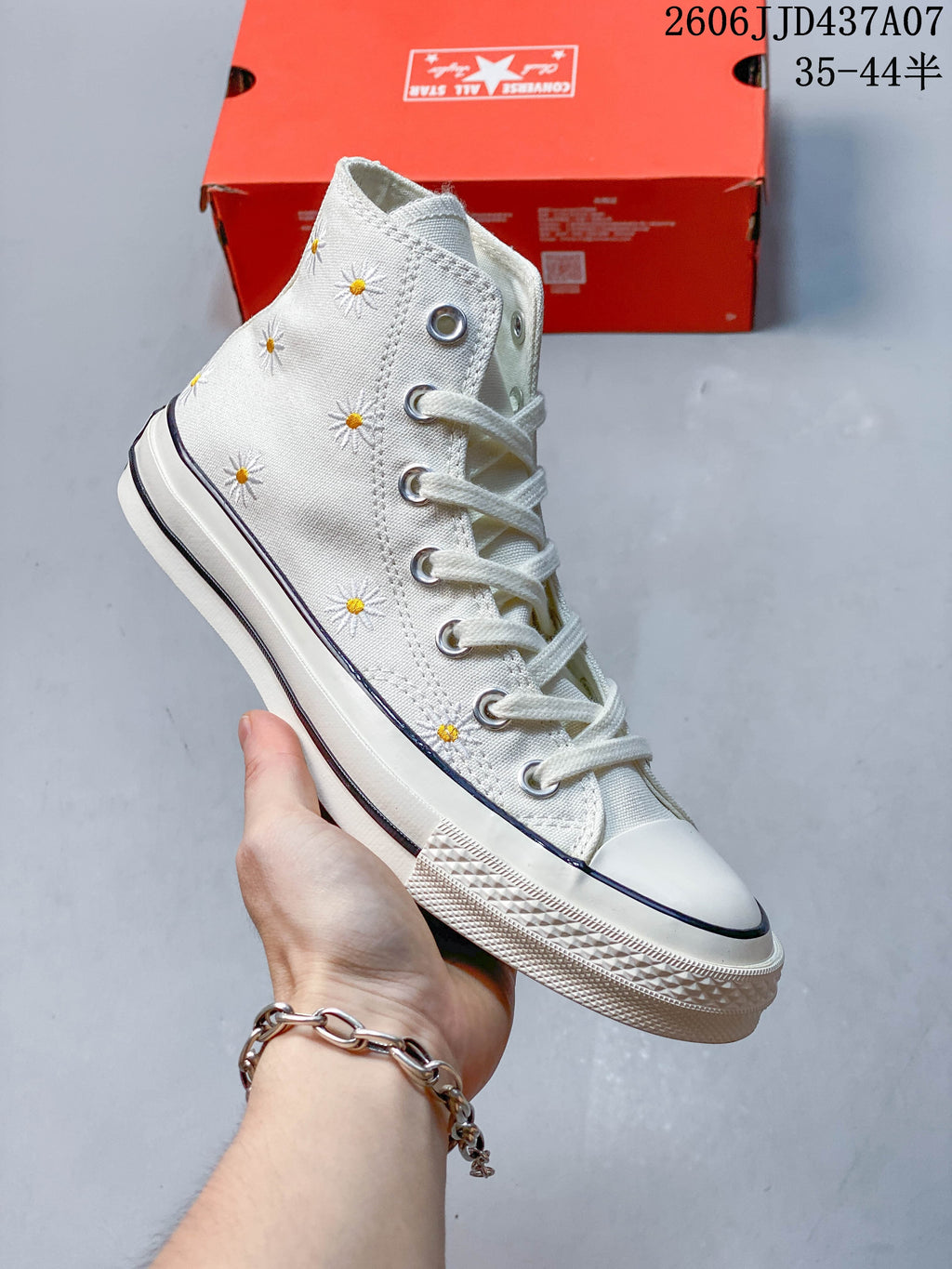 Close-up of the off-white sneaker showing embroidered daisies and metal eyelets