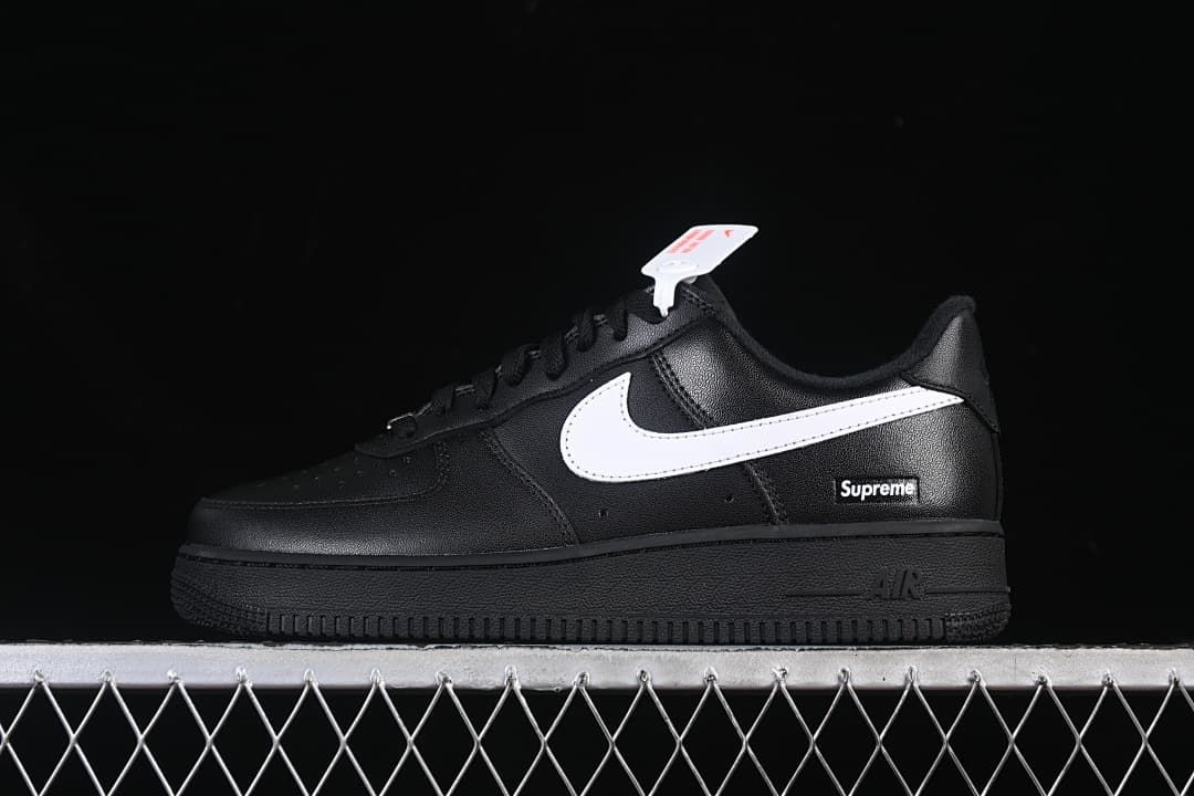 Side view of a black low-top Air Force 1 sneaker with a white Swoosh and Supreme heel detail