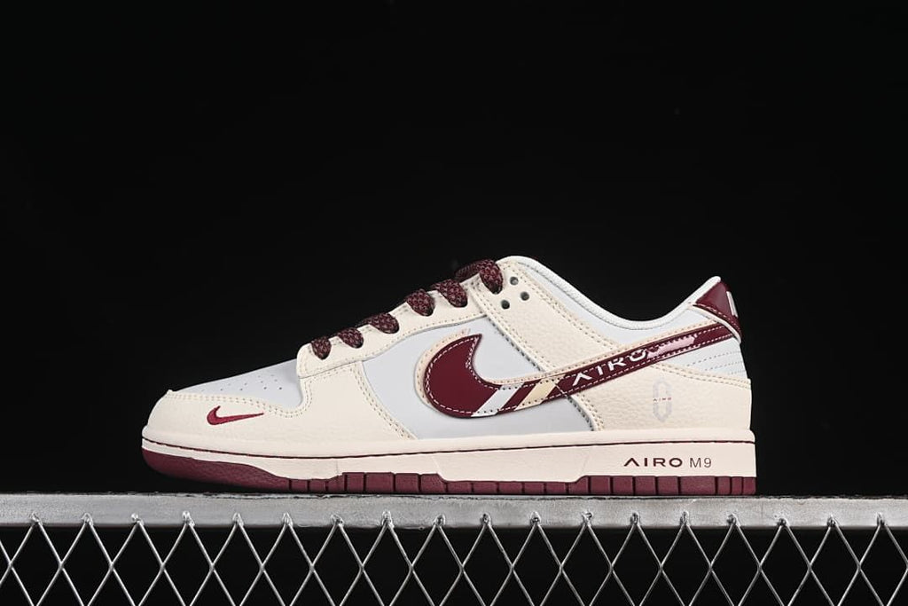 Side view of a cream and white low-top sneaker with burgundy accents and a two-tone sole