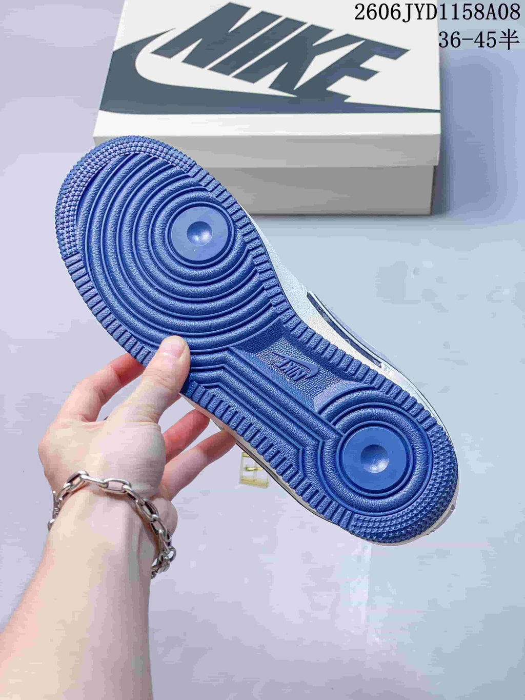 Blue outsole of a Nike Air Force 1 '07 Low sneaker beside its shoebox