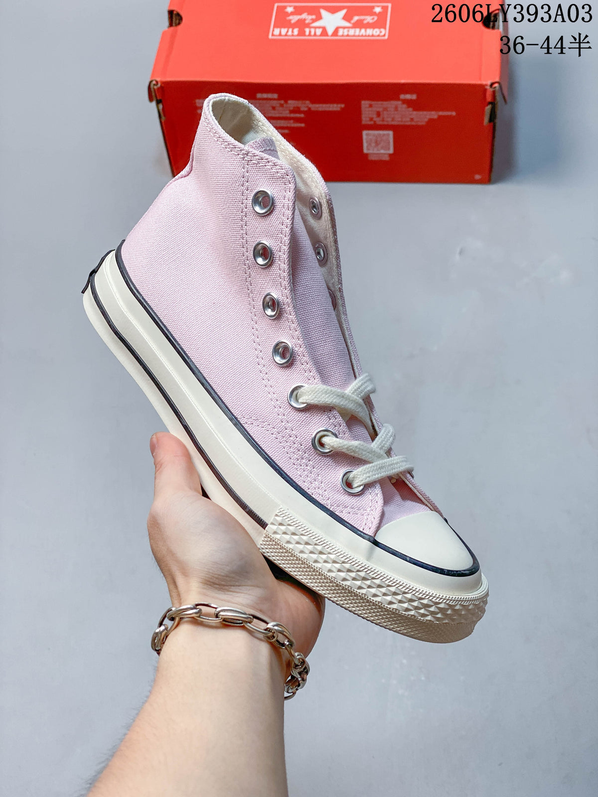 Pale pink high-top sneaker with white laces and rubber toe cap