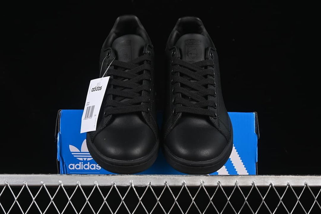 Front view of the pair of black sneakers displayed on the shoebox