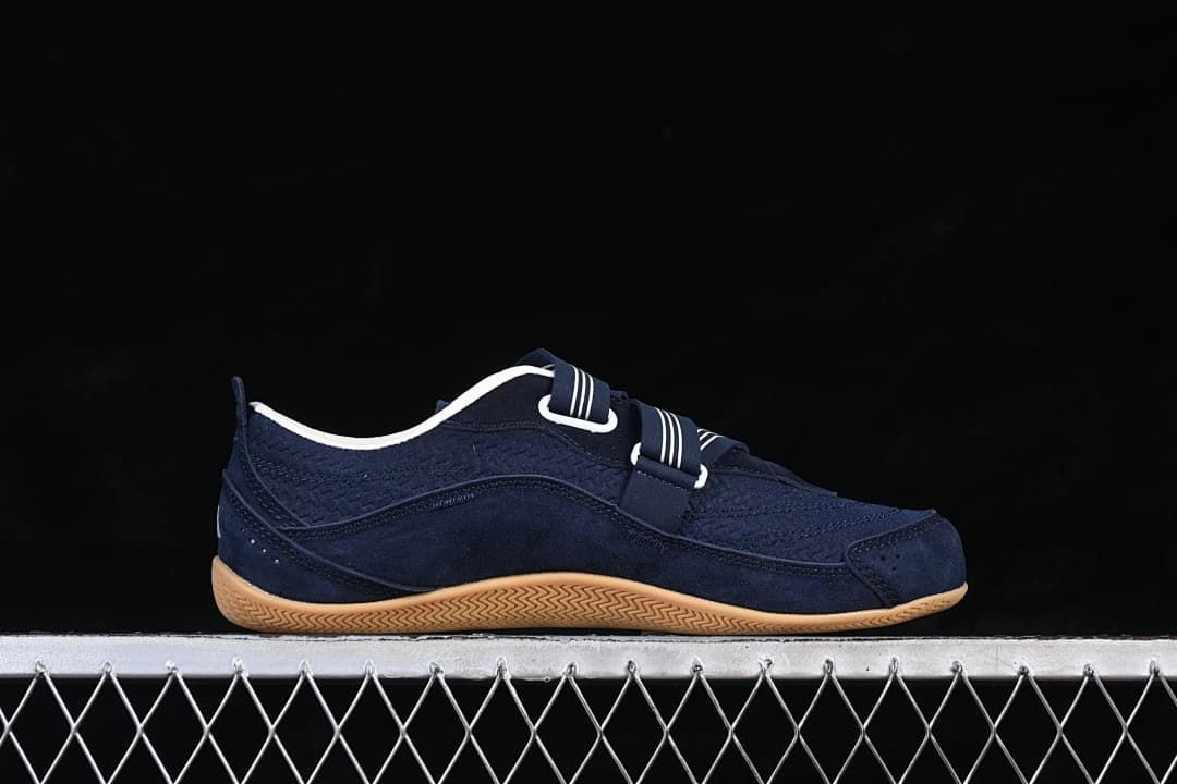 Side profile showing the navy upper, strap closure, and gum-colored sole.