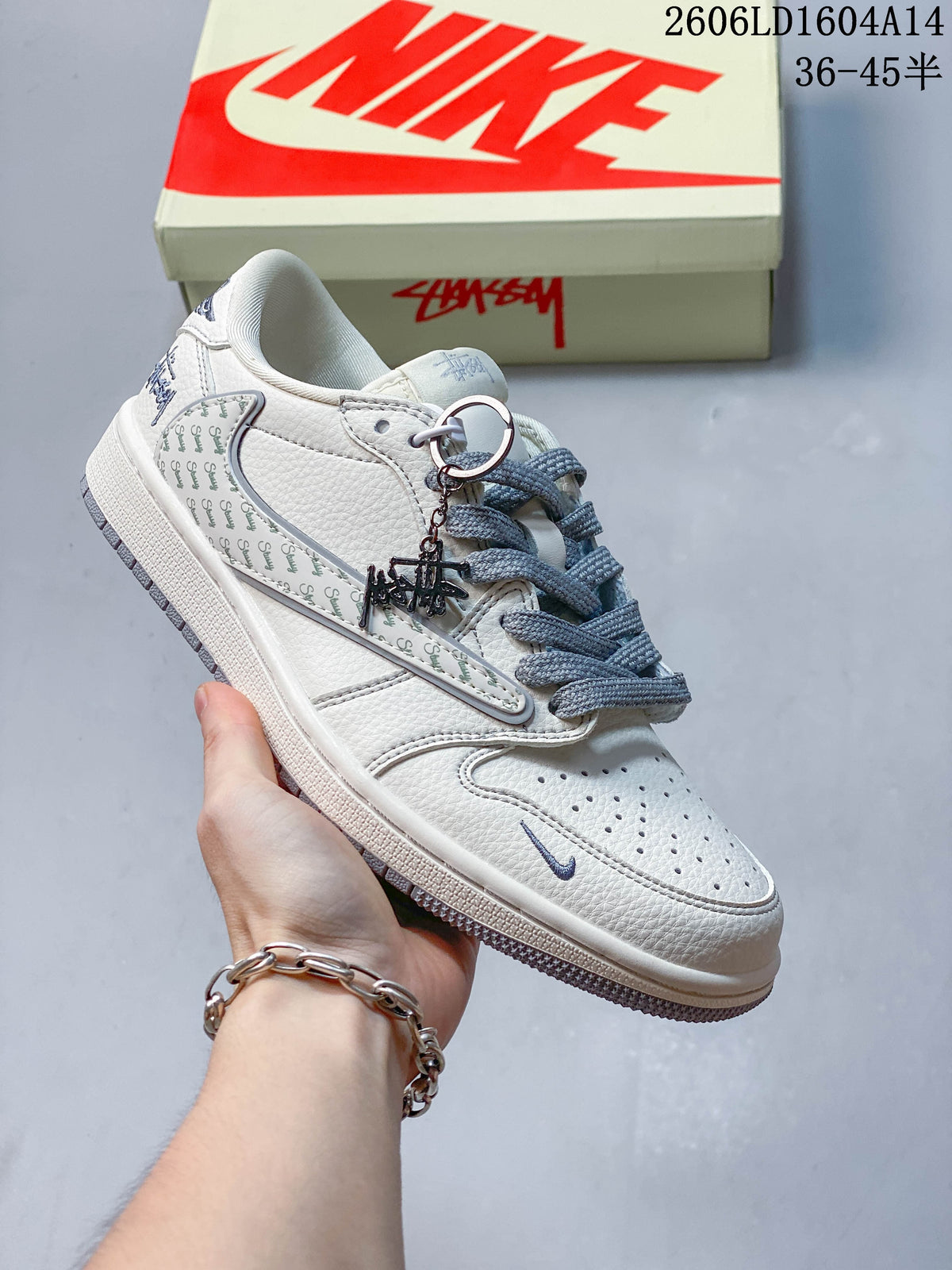 Side view of a white sneaker with gray laces, printed side panel, and decorative charm