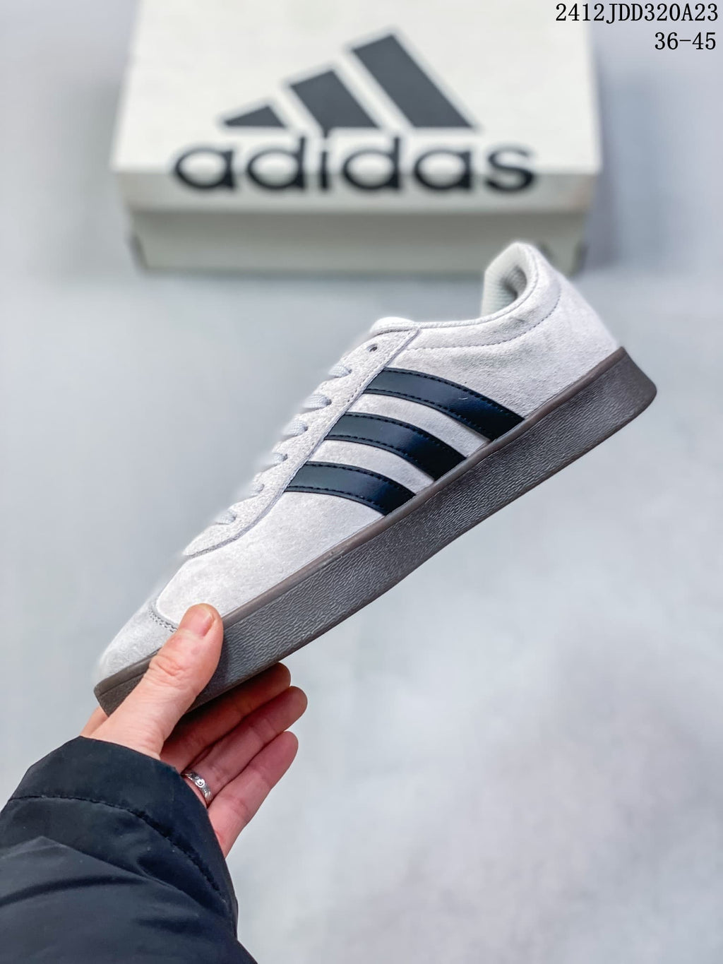 Side profile of the light grey Adidas sneaker with black stripes and dark sole