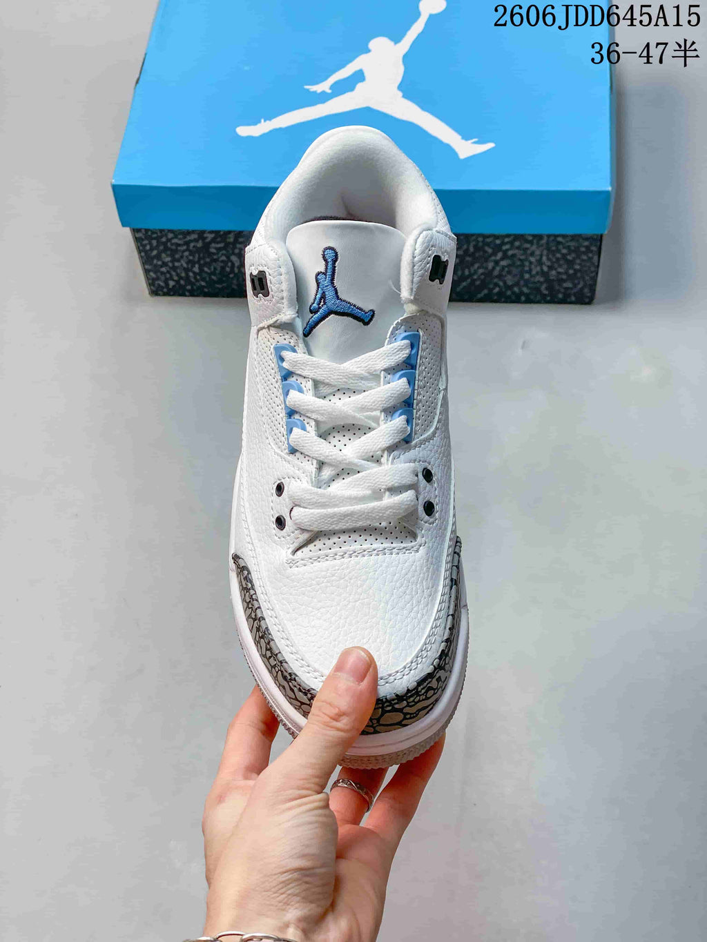 Front view of the sneaker showing white laces, perforations and blue tongue logo.