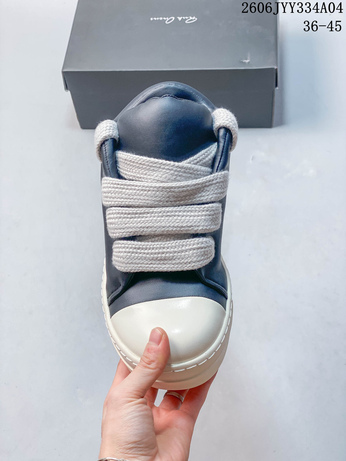 Front view of a navy sneaker with wide ivory laces and a rounded toe cap