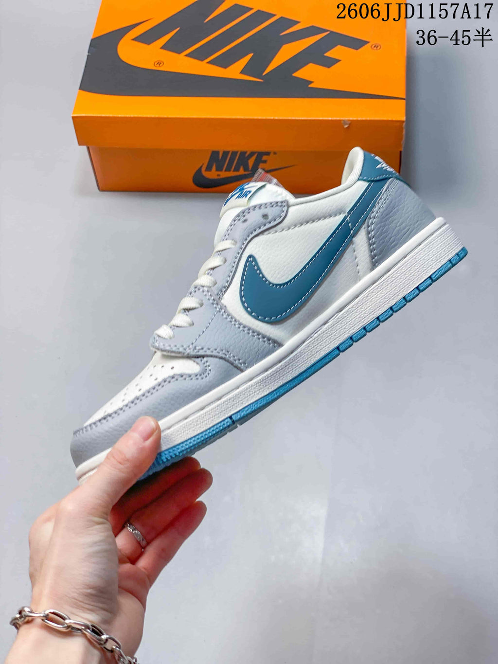 Side view of the white and grey sneaker with a blue side swoosh and blue outsole.