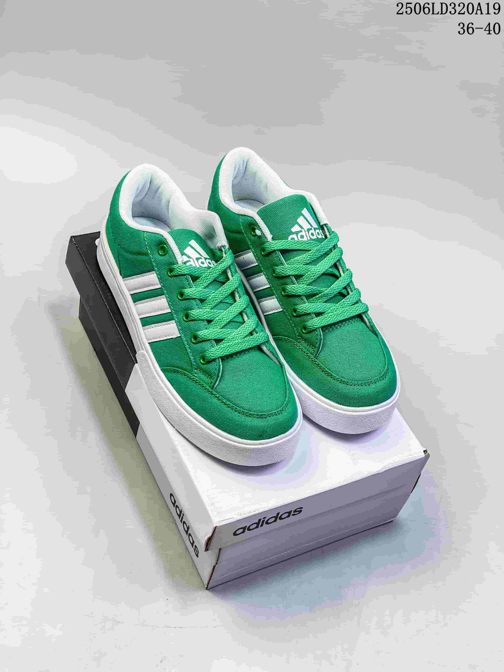 Pair of green Adidas low-top sneakers with white stripes and white soles, shown on a shoebox