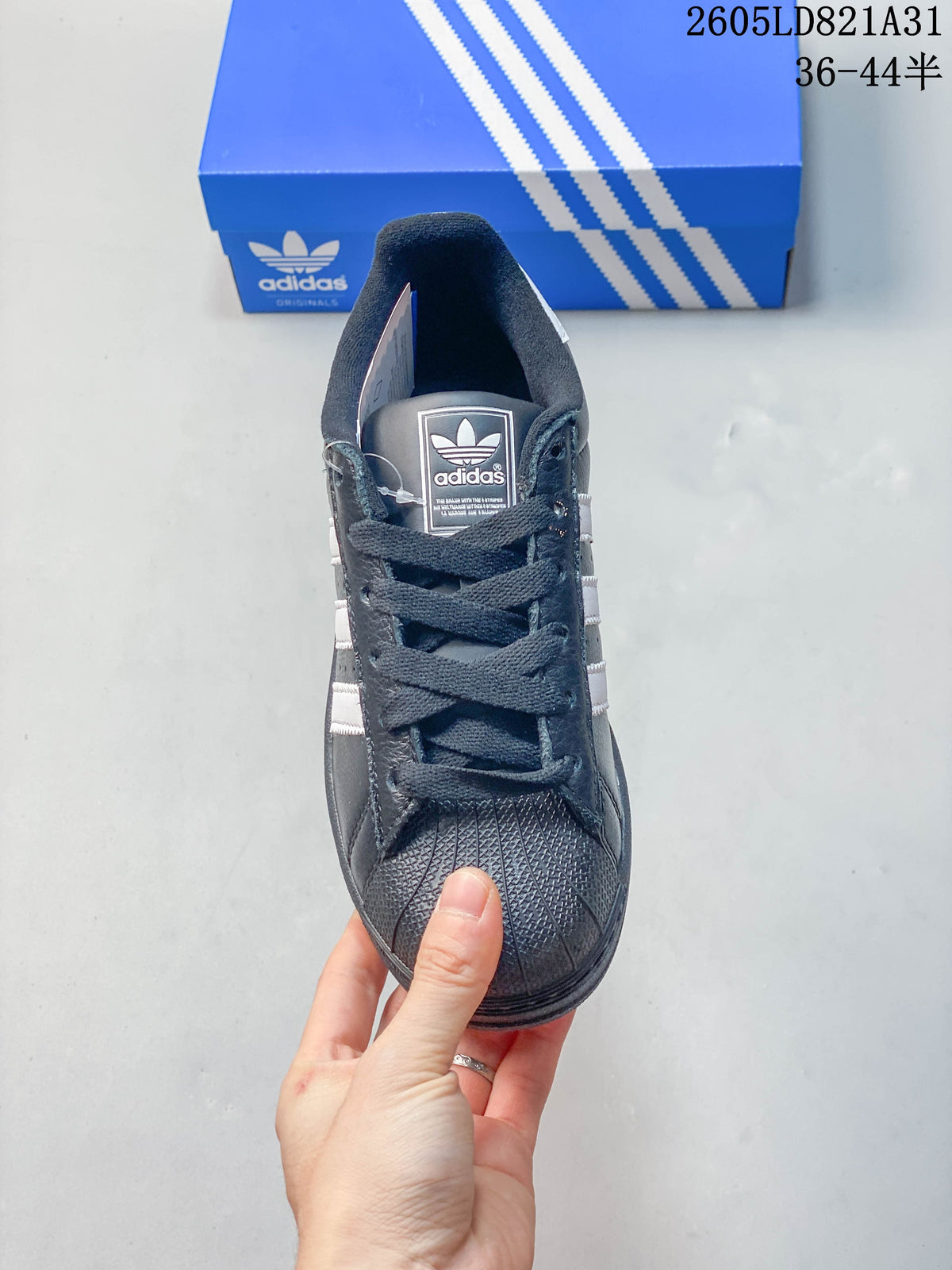 Front view of a dark Adidas Superstar sneaker with laces and a textured shell toe.