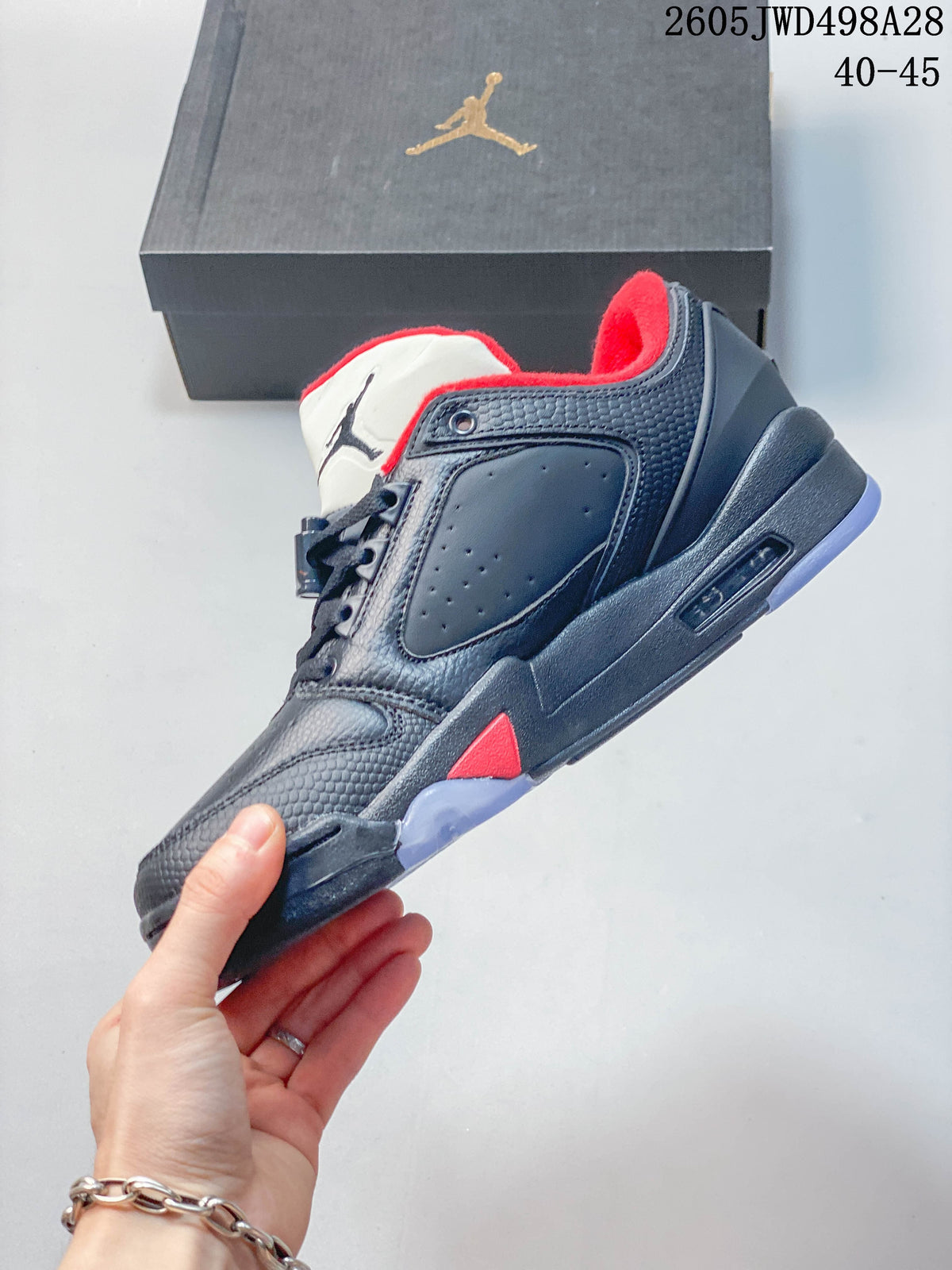 Side view of a dark Jordan low-top sneaker with red accents and a light-colored outsole.