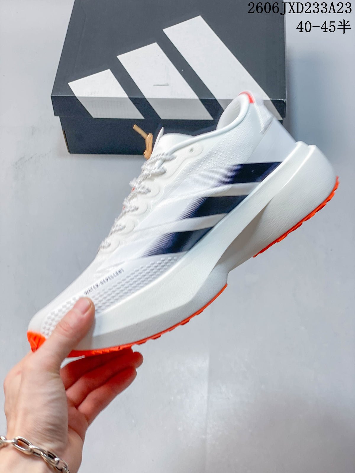 Side view of a white low-top running shoe with dark stripes and orange outsole accents