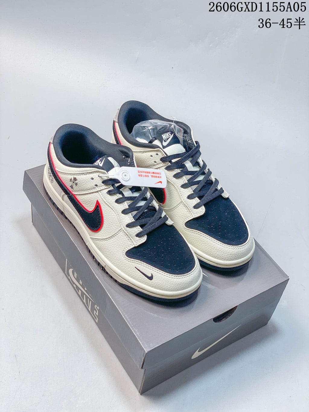 Pair of cream, navy and red low-top sneakers displayed on a shoe box