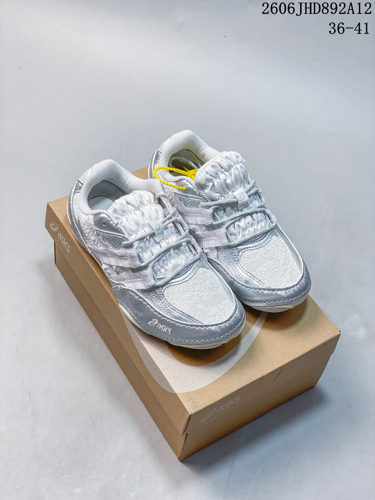 Pair of silver and light gray ASICS Hypersync sneakers shown on a shoebox