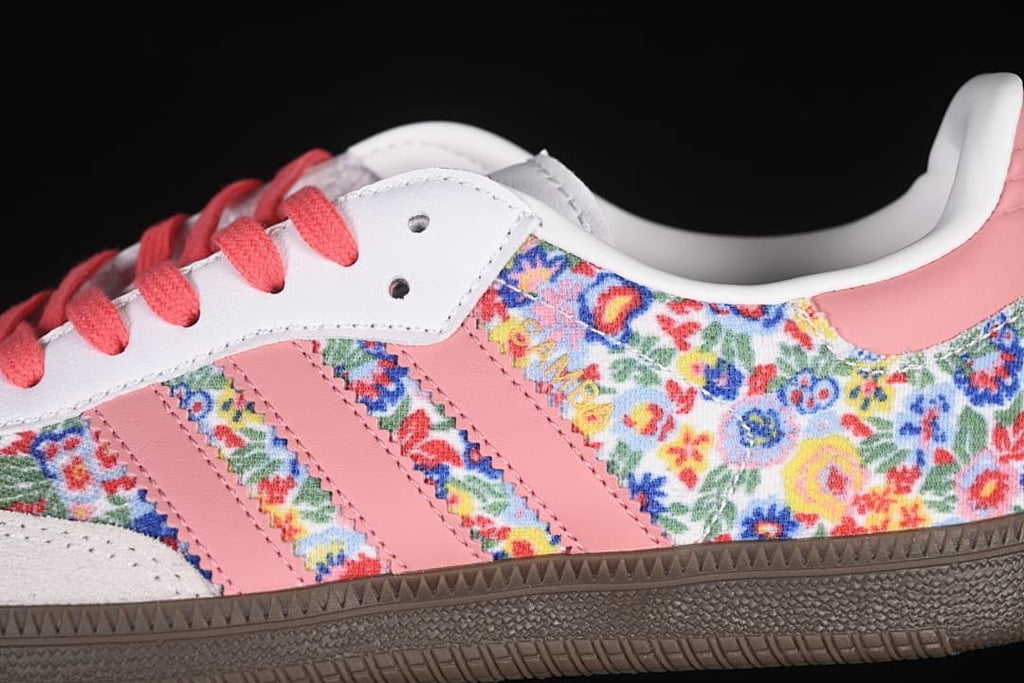 Close-up of floral-print side panels, pink stripes, white overlays, and coral laces