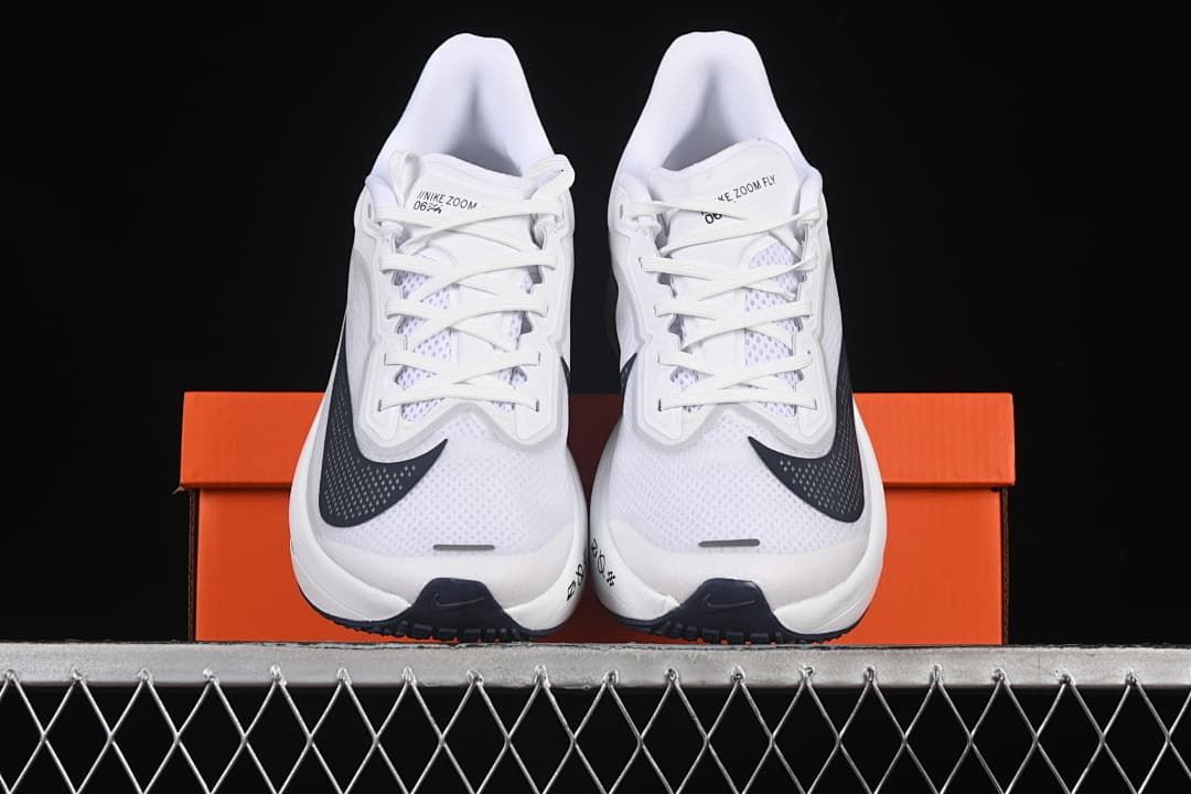 Front view of a pair of white running shoes displayed on an orange box.
