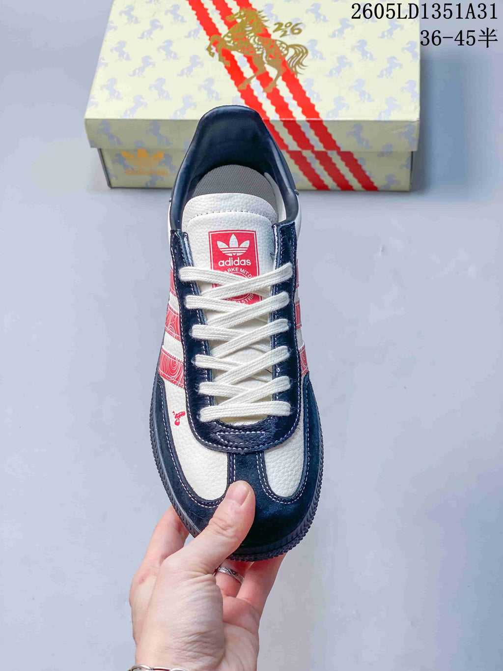 Top view of the sneaker showing white laces, a red tongue label, and navy trim