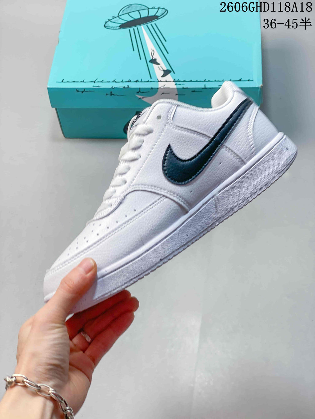 Side view of a white low-top sneaker with a dark logo and graphic accents.