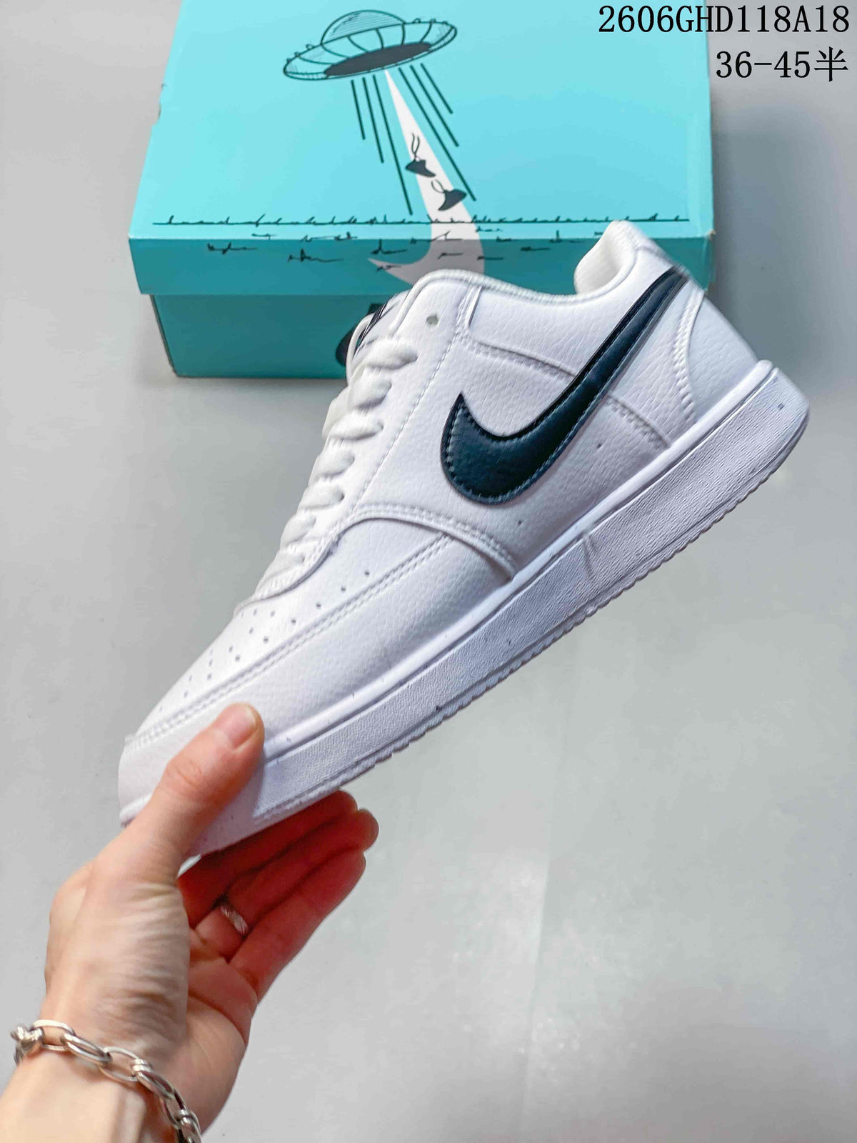 Side view of a white low-top sneaker with a dark logo and graphic accents.