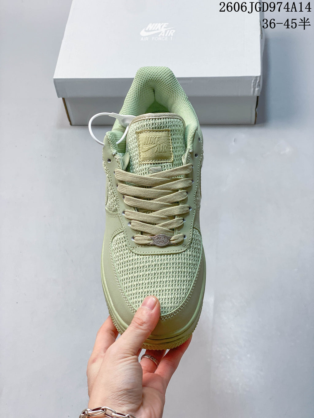 Front view of a pale green sneaker with matching laces and woven-look toe panel