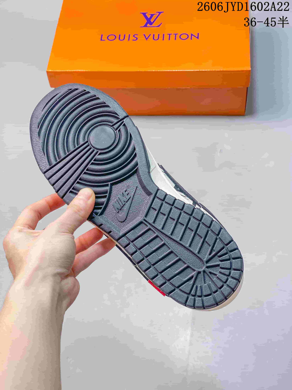 Close-up of the dark patterned outsole with an orange branded box in the background
