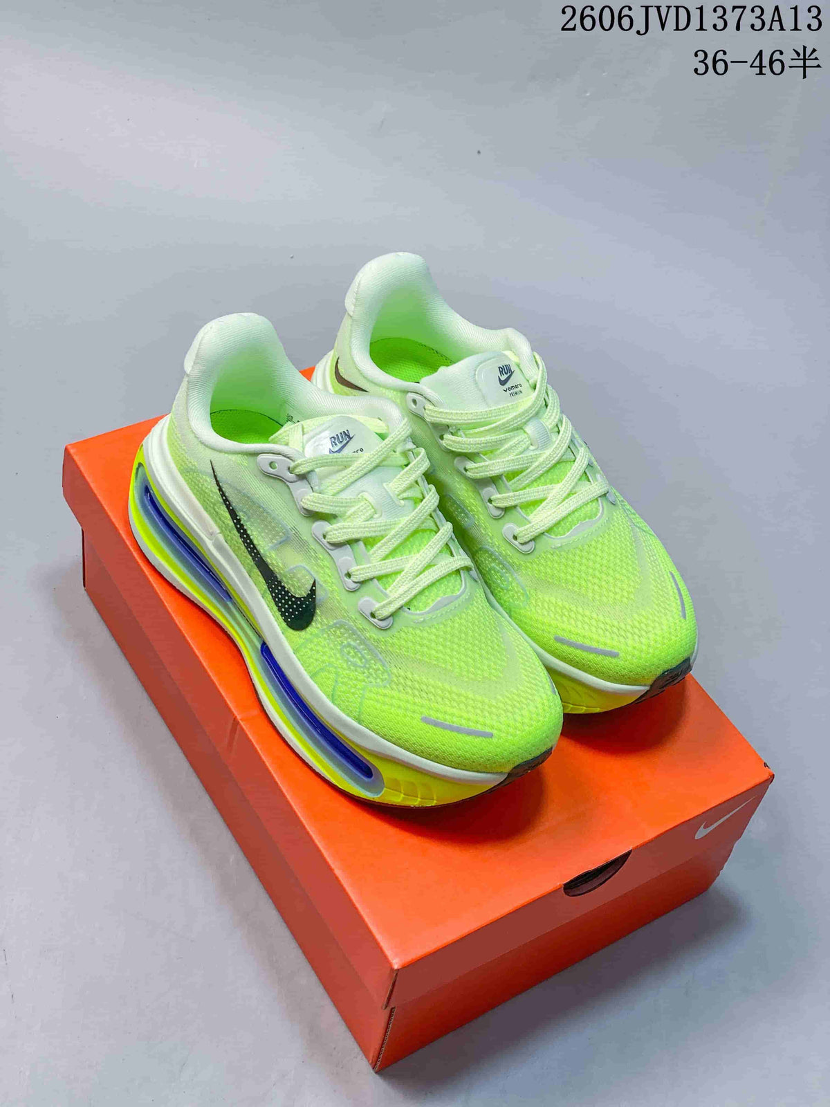 Pair of fluorescent green Nike Vomero Premium running shoes on an orange shoebox
