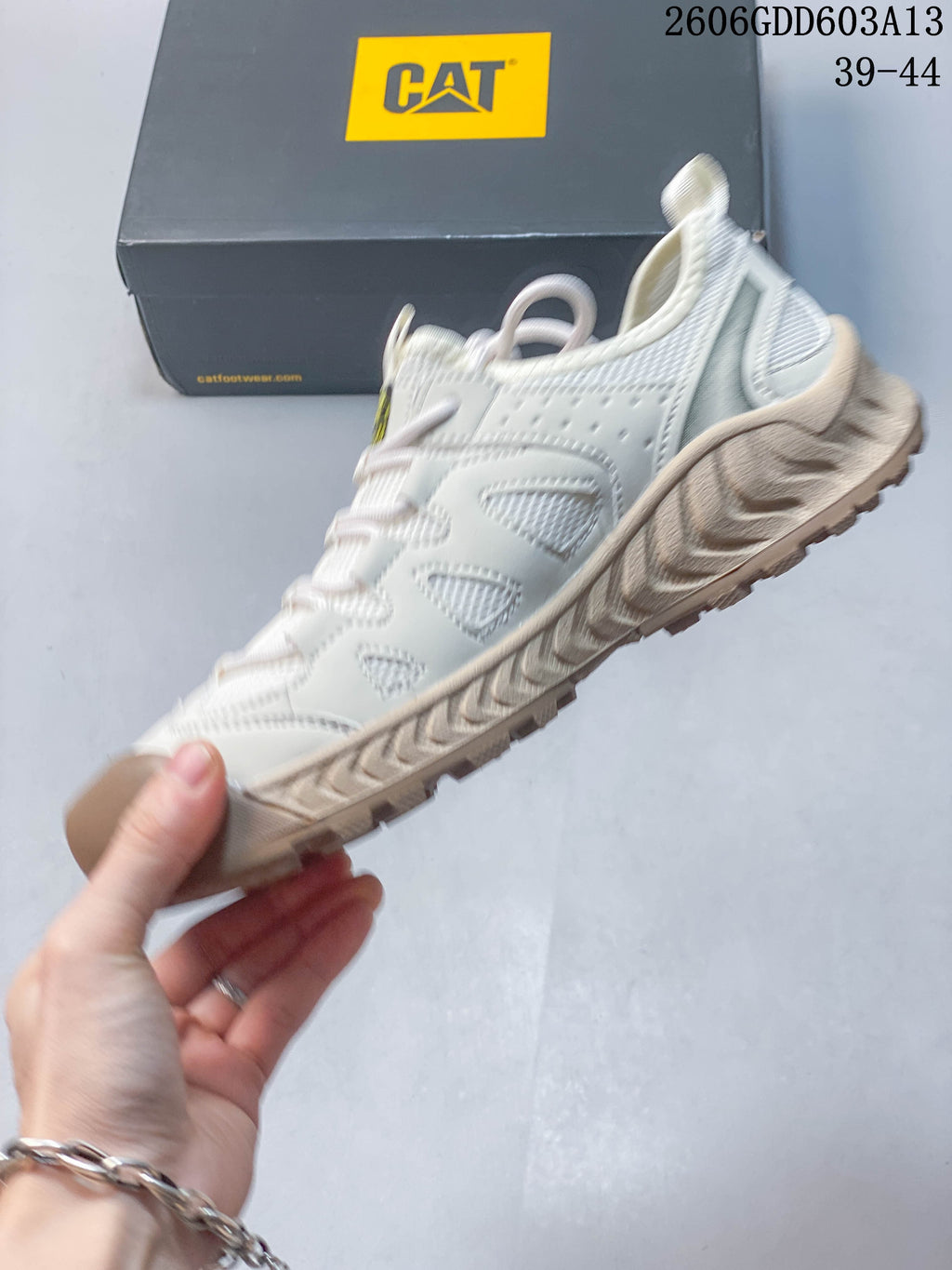 Side view of a white CAT sneaker with mesh panels and beige textured outsole