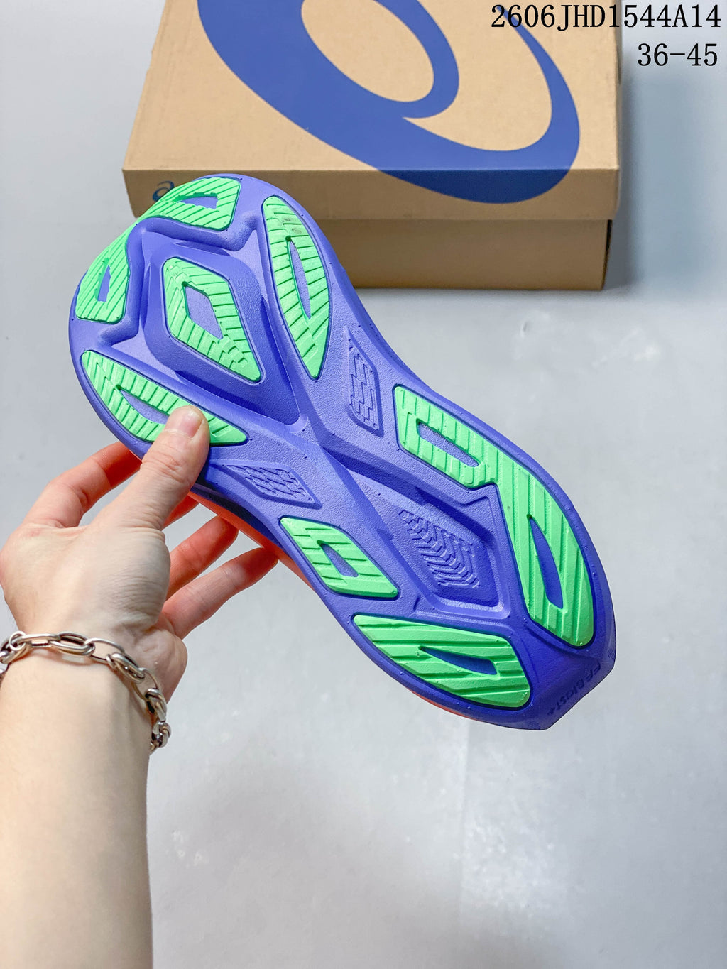 Underside of a purple running shoe with green outsole sections