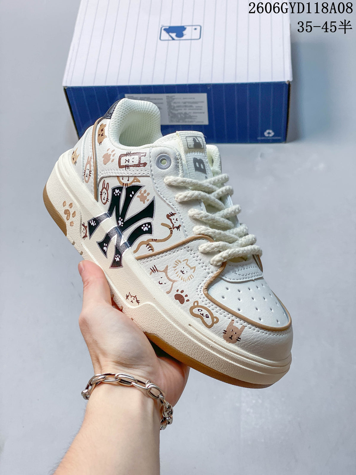 Angled view of the cream sneaker with cat illustrations and a gum-tone outsole