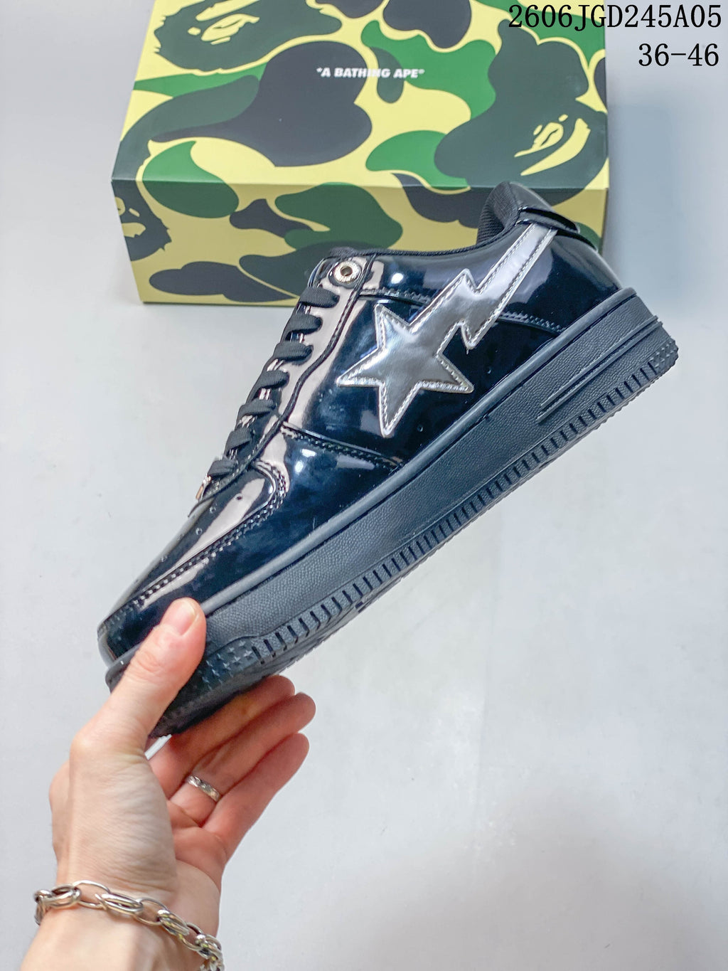 Side view of a glossy navy low-top sneaker with a silver star panel and dark sole