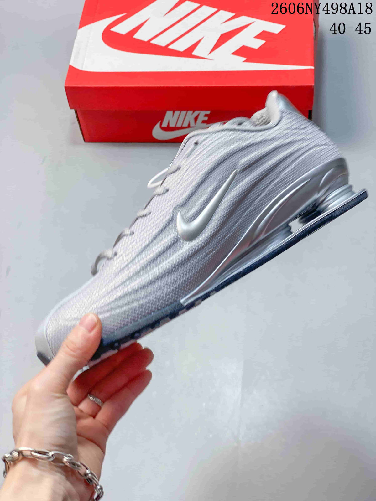Side view of a silver Nike Shox TL sneaker with metallic Swoosh and heel columns