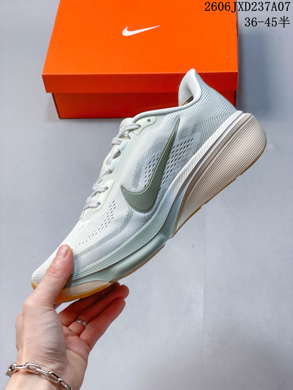 Side view of a light-colored Nike Pegasus 42 running shoe with muted green swoosh and midsole details.