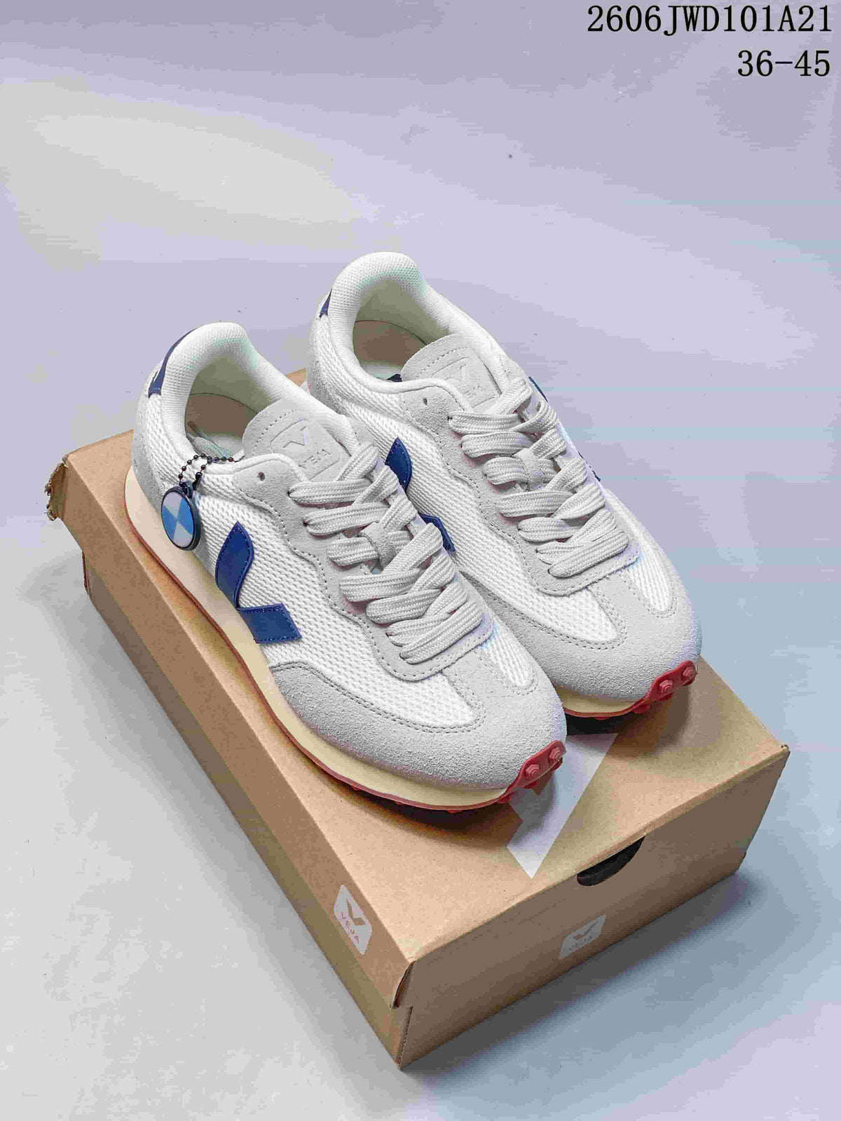 Pair of white and light gray Veja sneakers with blue side logos, shown on a shoe box
