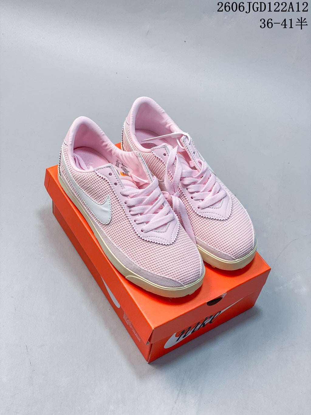 Pink Nike Astro Grabber sneakers displayed on an orange shoe box