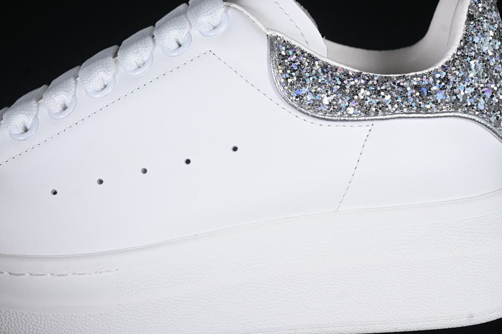 Side detail of the white upper, lace eyelets, and glitter heel panel.