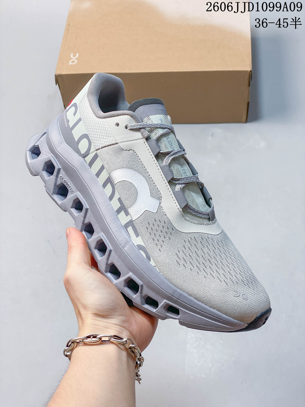 Side view of a light gray On Cloudmonster Void shoe showing its lace-up design and sculpted open-channel sole.