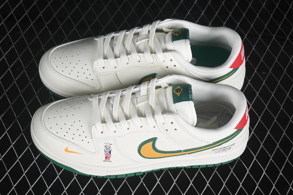 Top and angled view of a pair of white Nike SB Dunk Low sneakers showing perforated toe boxes, white laces, green tongue details, and multicolor accents.