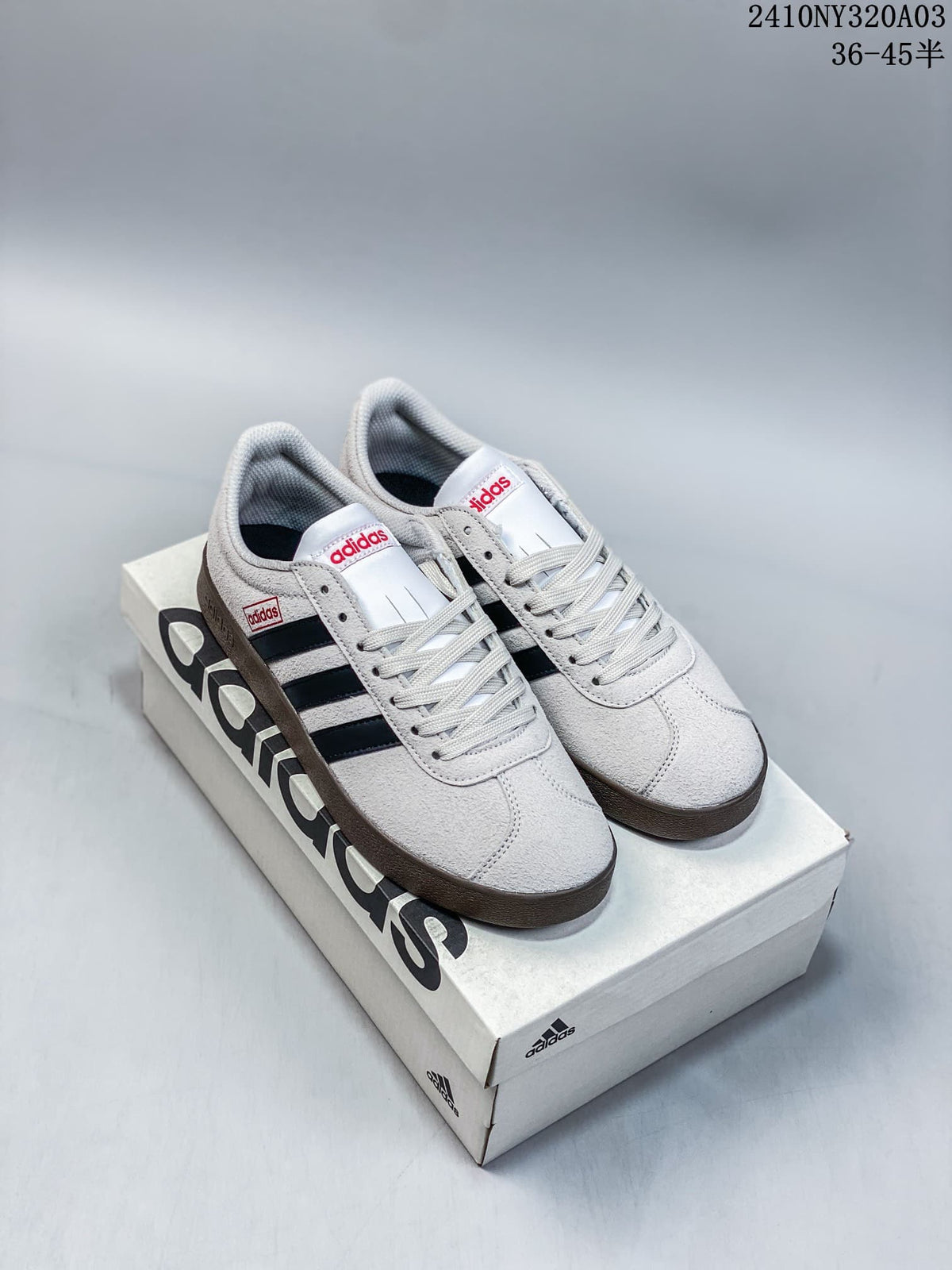 Pair of light grey Adidas Neo VL Court 2.0 sneakers with dark side stripes and brown-toned soles, displayed on a shoebox