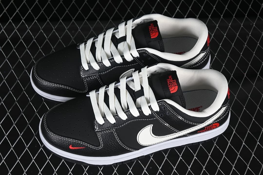 Pair of black low-top sneakers shown from above, with white laces, white Swooshes, and red accent graphics.
