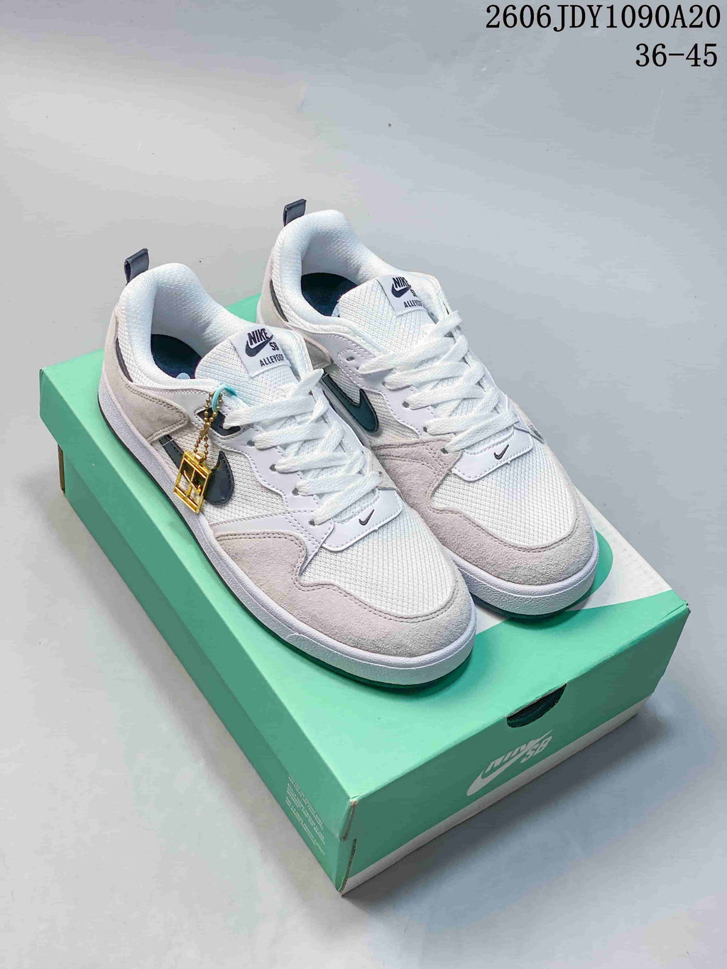 Pair of white and light grey Nike SB Alleyoop low-top shoes on a green box
