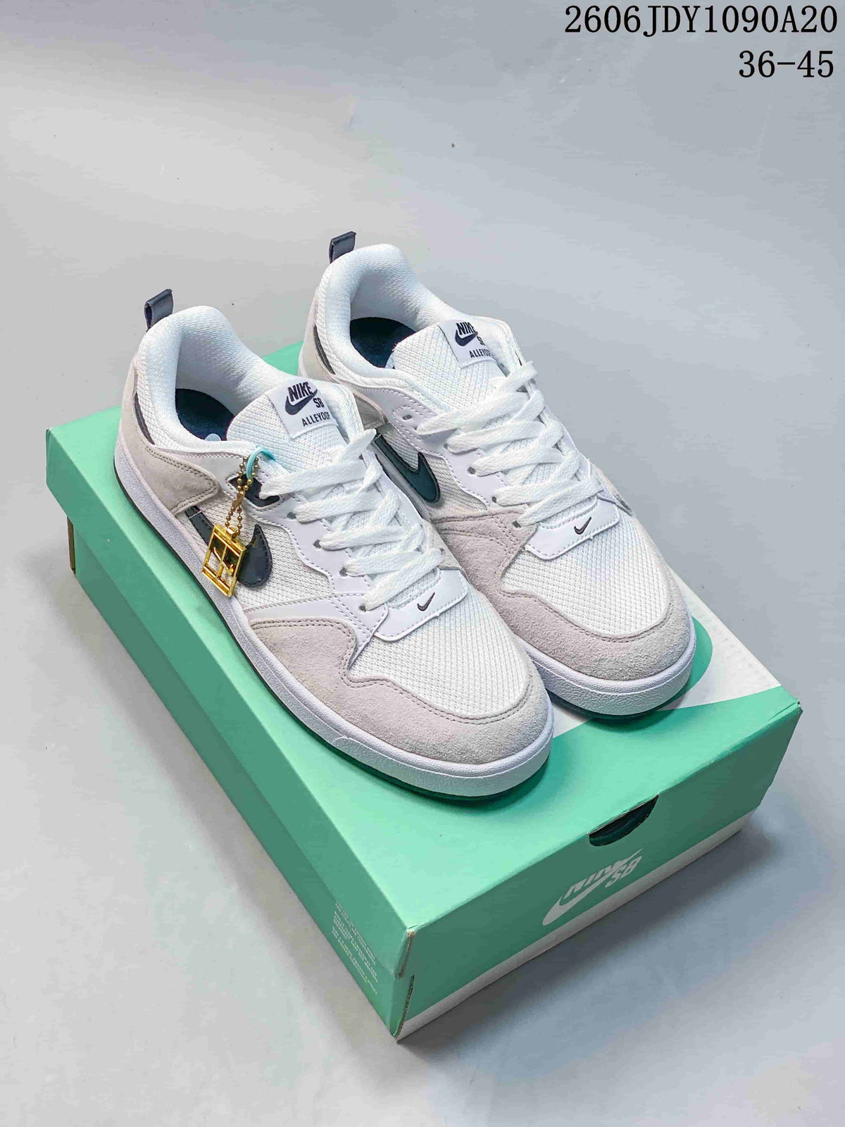 Pair of white and light grey Nike SB Alleyoop low-top shoes on a green box