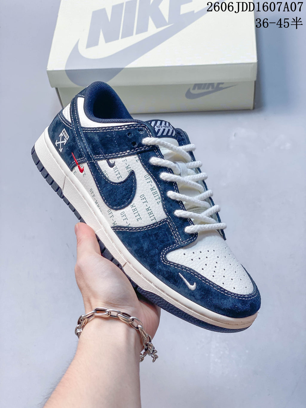 Close-up of a navy and white low-top sneaker with text-print panels and contrasting accents.