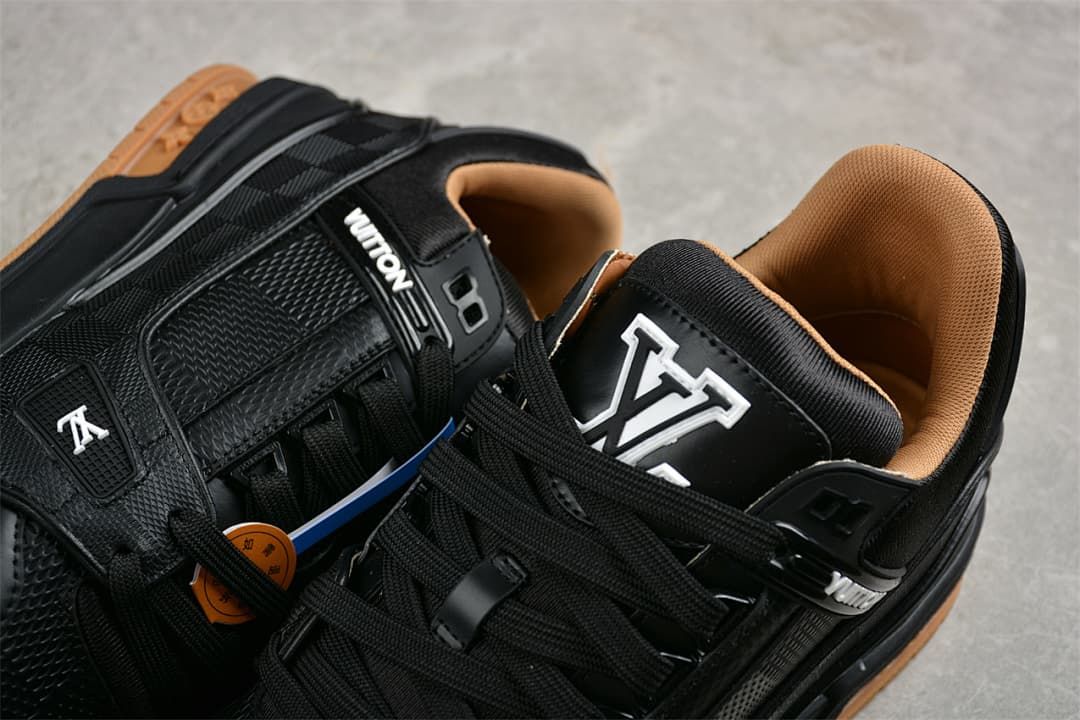 Close-up of black sneakers showing logo details, laces and tan-colored lining