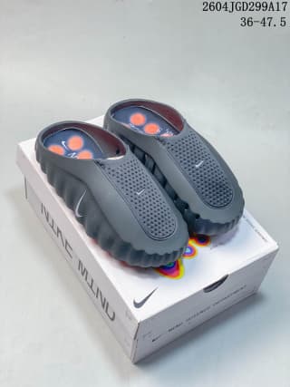 Dark gray Nike Mind slides with orange footbed nodes displayed on a box; the image marking shows a size range of 36–47.5.