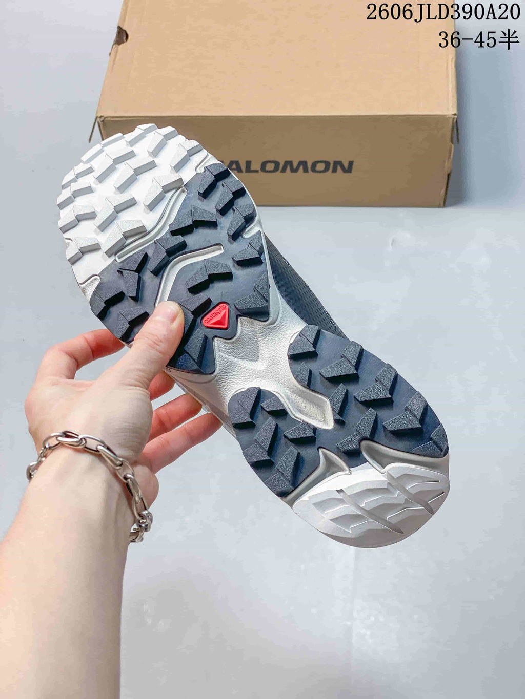 Close-up of the shoe outsole showing deep lugs and a red Salomon logo.