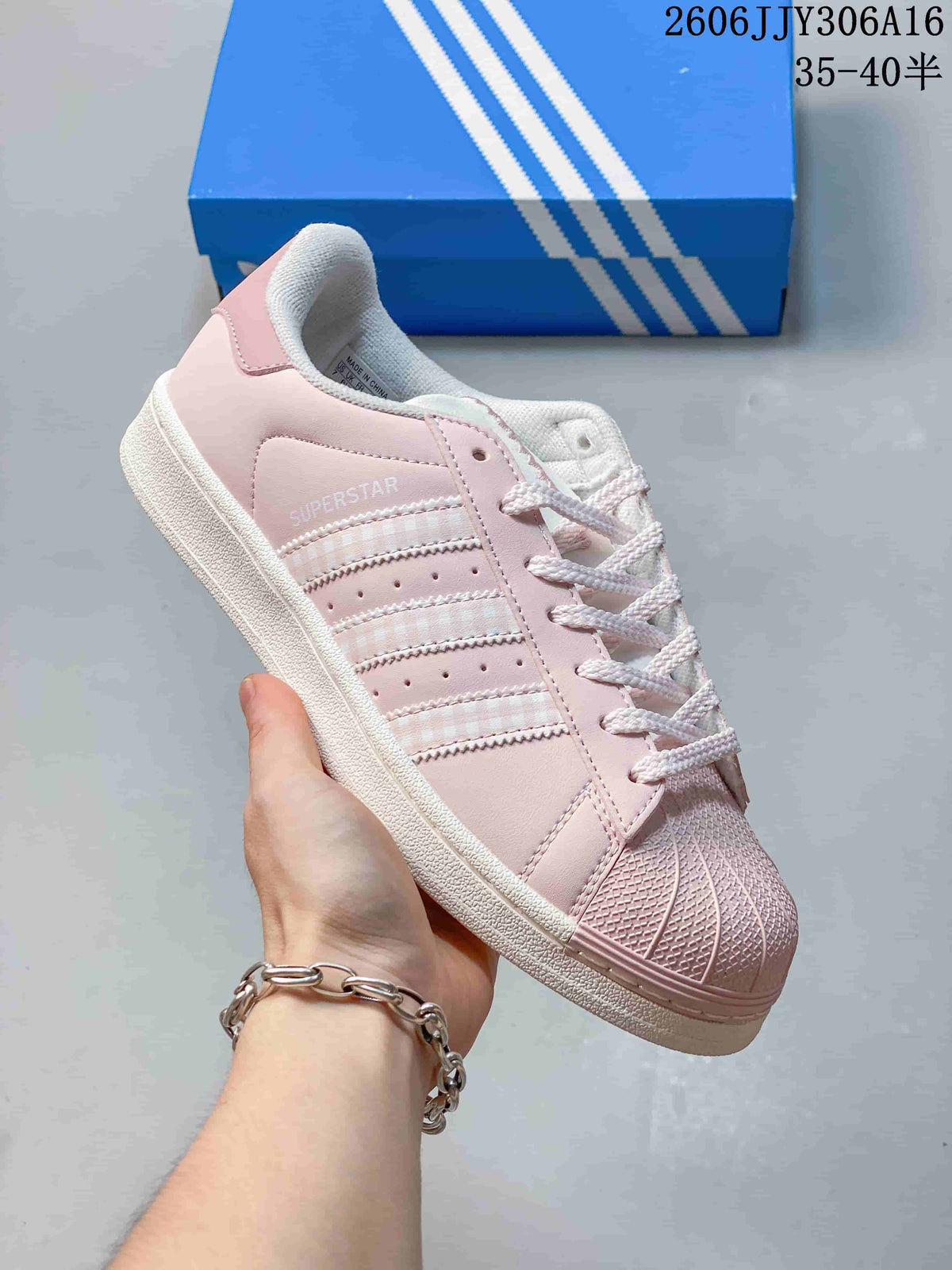 Close side view of a pale pink Superstar sneaker with checked stripes