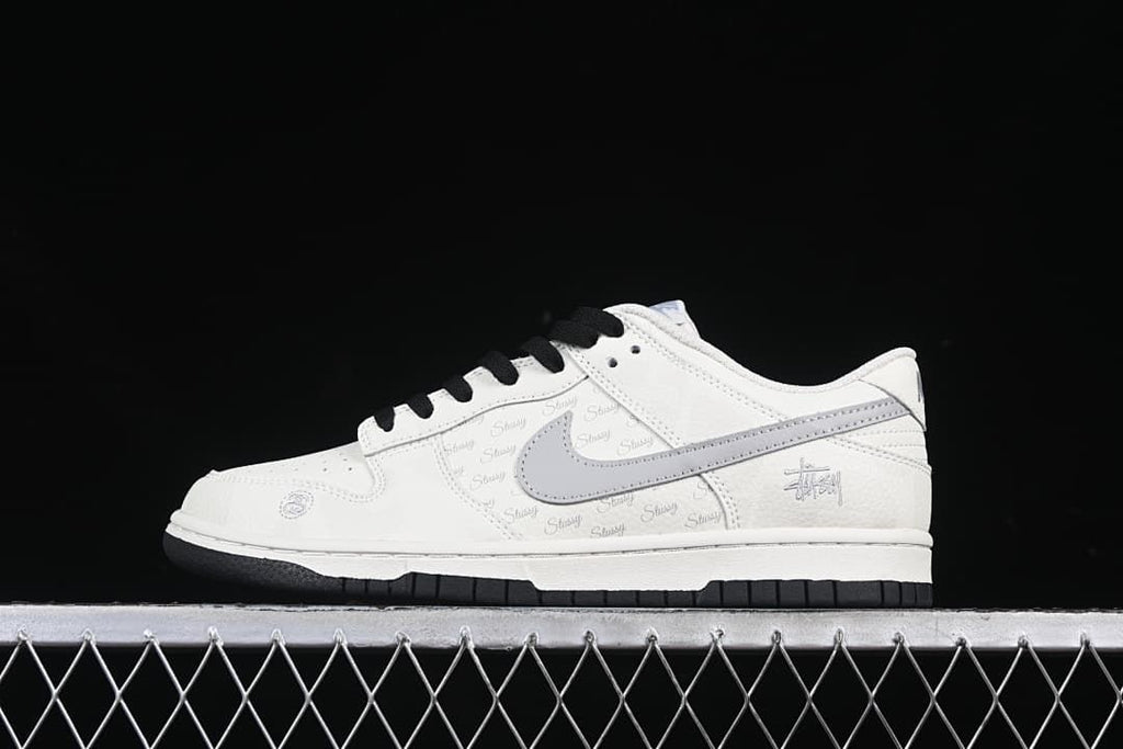 Side profile of the white and grey Nike Dunk Low sneaker with black laces.