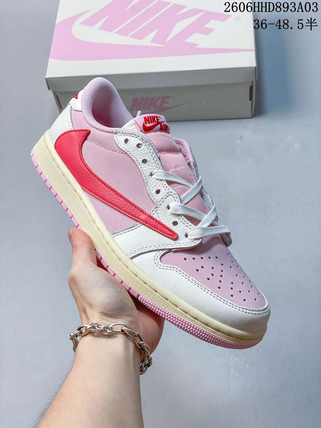 Angled side view of a pink and white low-top sneaker with a contrasting red Swoosh; image overlay states a size range.